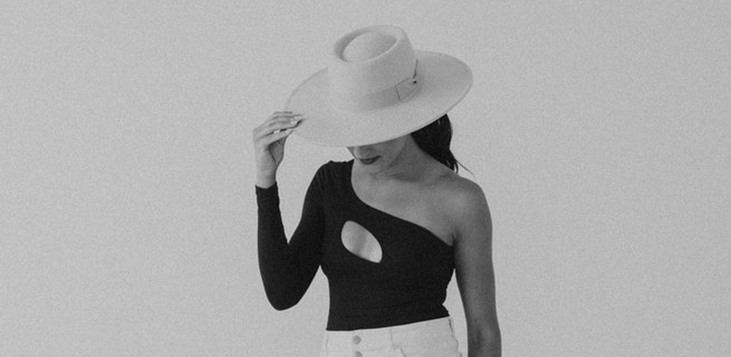 Macie Renae in white trousers and a wide-brimmed hat