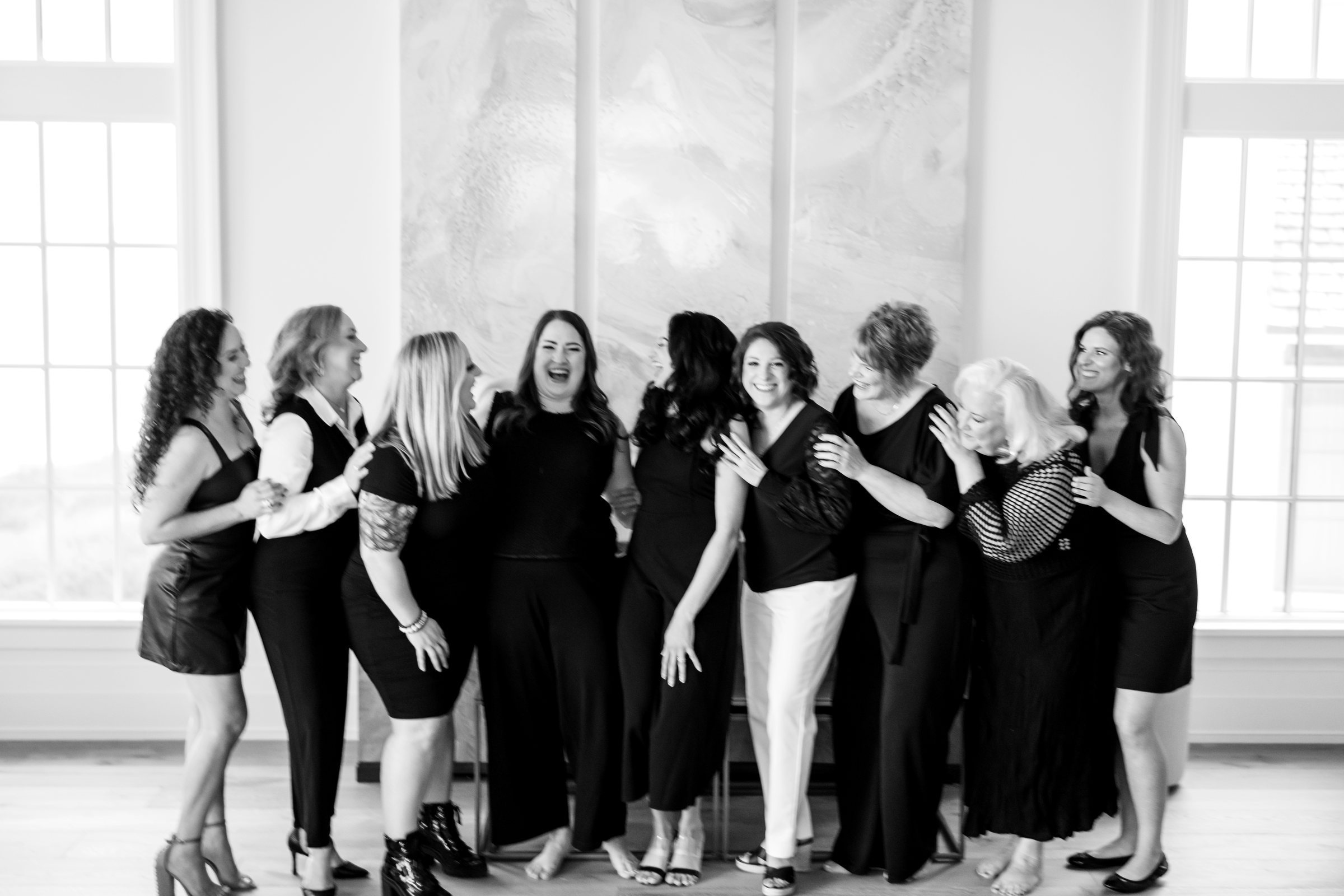 Retreat group in black, laughing together in front of tall windows
