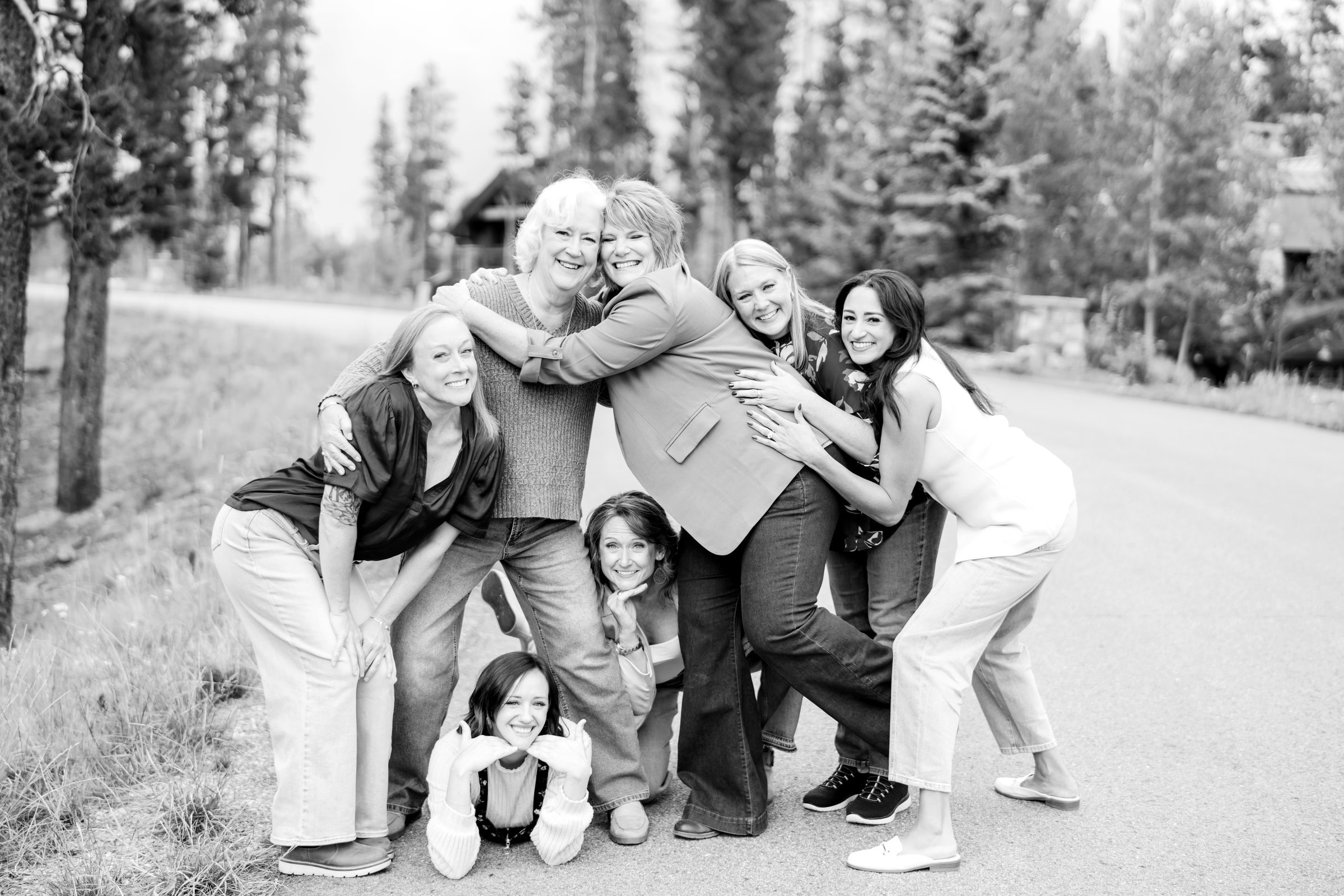 Retreat group holding on to each other, laughing, among the pines