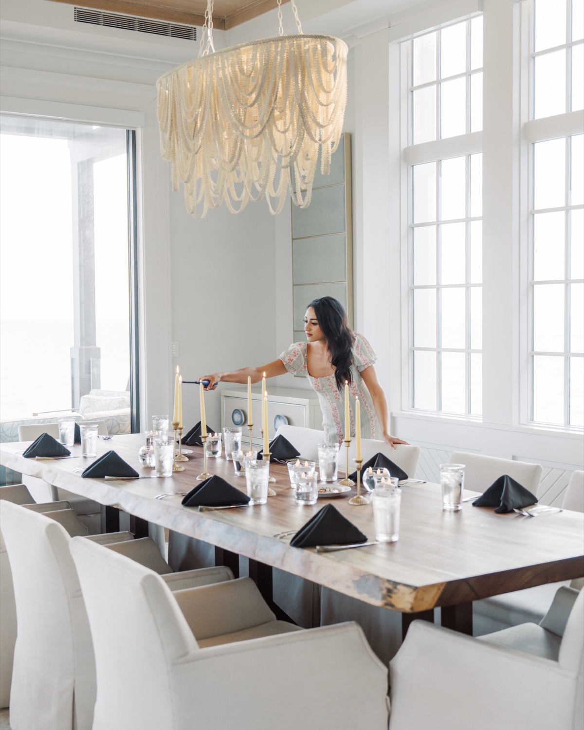 Macie setting a long dining table beneath a statement chandelier at the retreat house