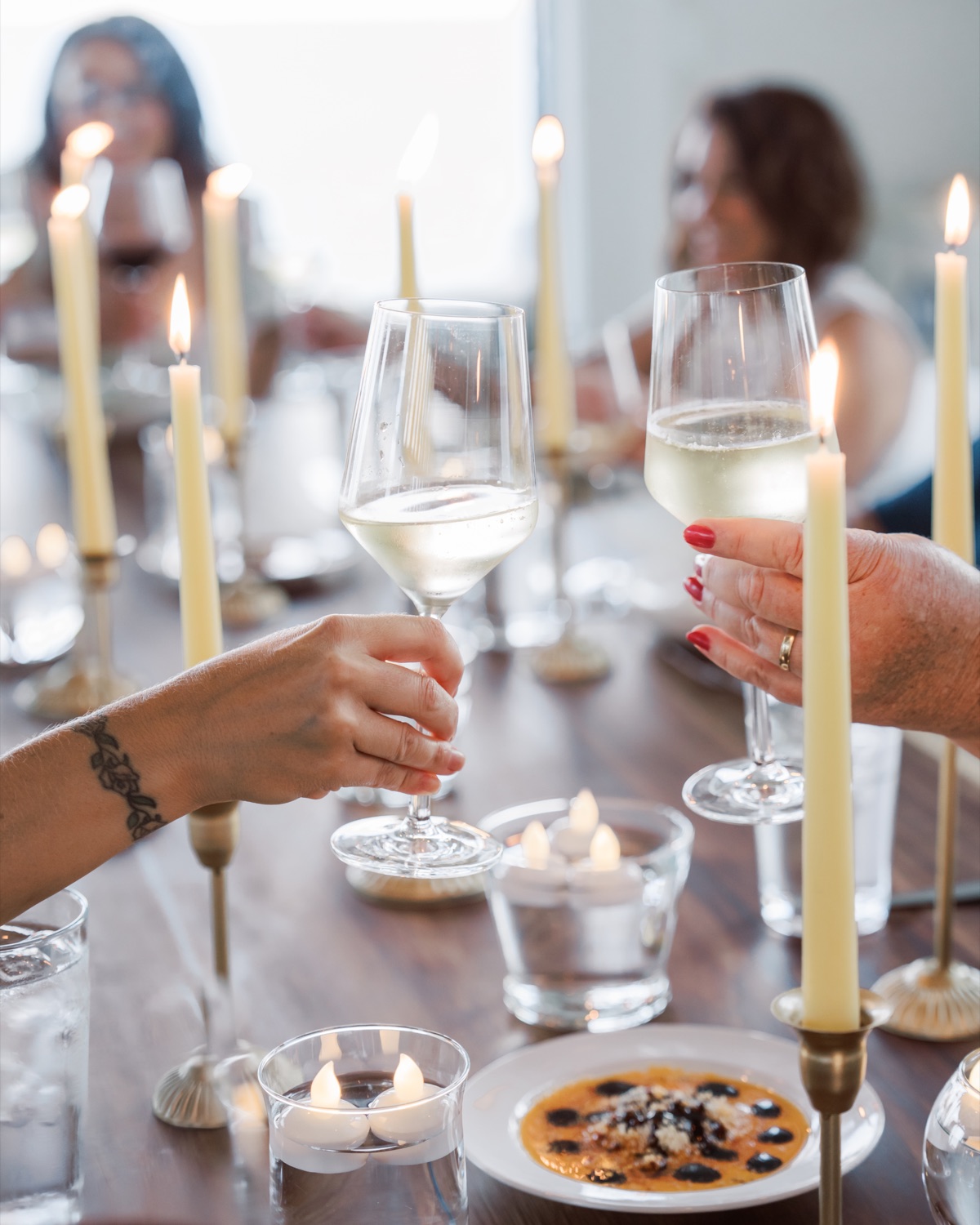 Retreat guests raising wine glasses across a candlelit dinner table