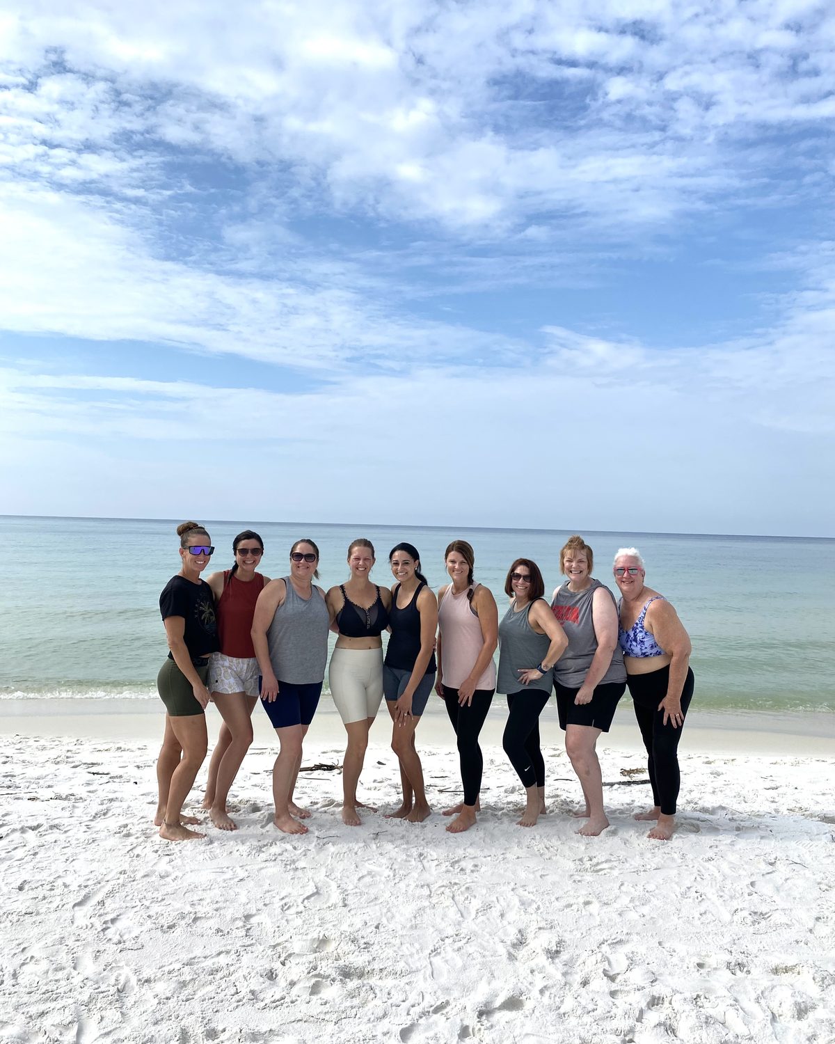 Nine Hybrid Experience retreat guests together on the white sand at Alys Beach